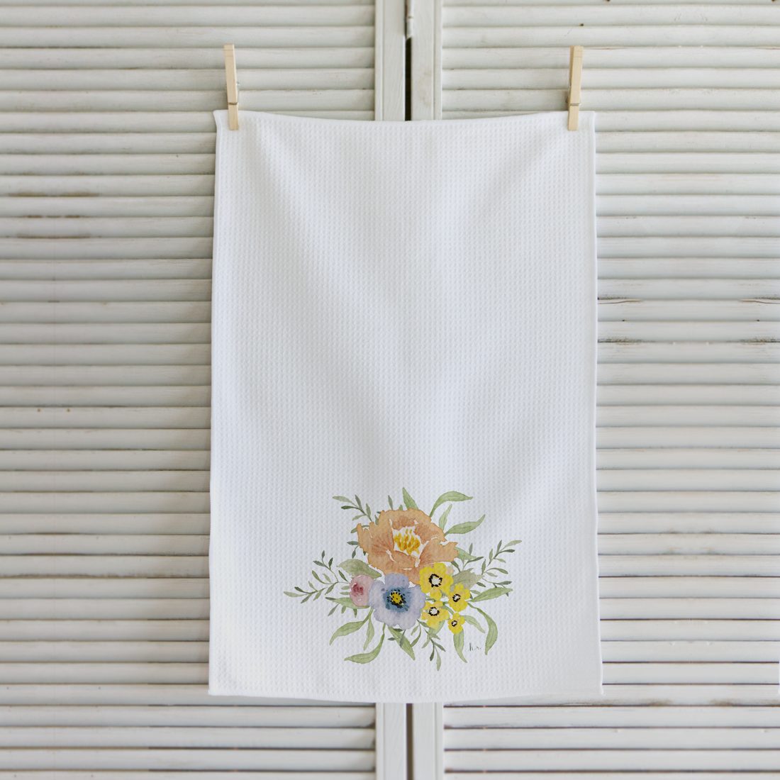 White towel with floral design hanging on a wooden surface