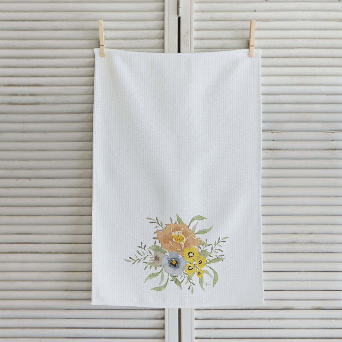 White towel with floral design hanging on a wooden surface