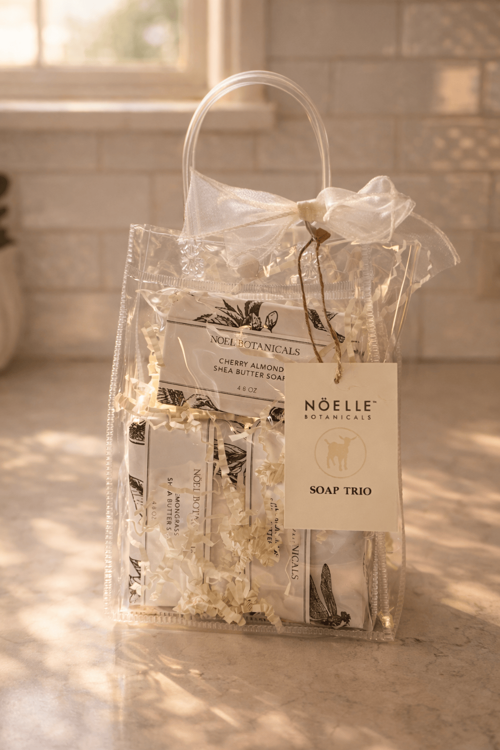 NOELLE Botanicals soap trio packaging with a clear bag on a light surface.