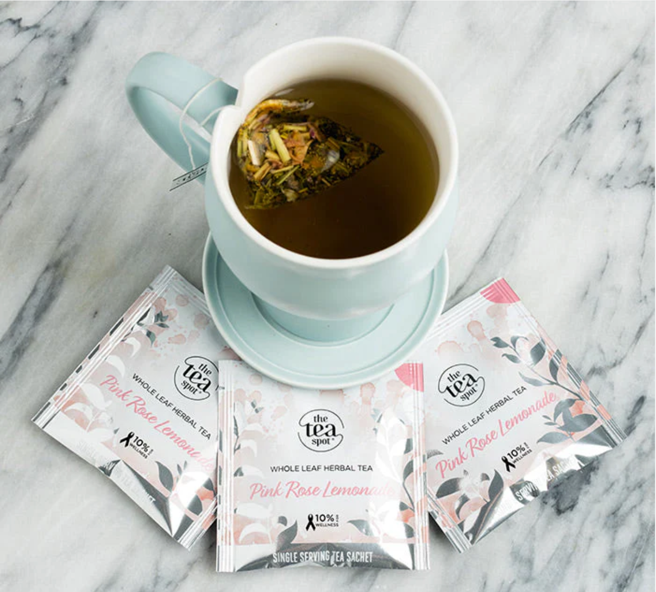 Tea cup with a tea bag and pink tea packages on a marble surface