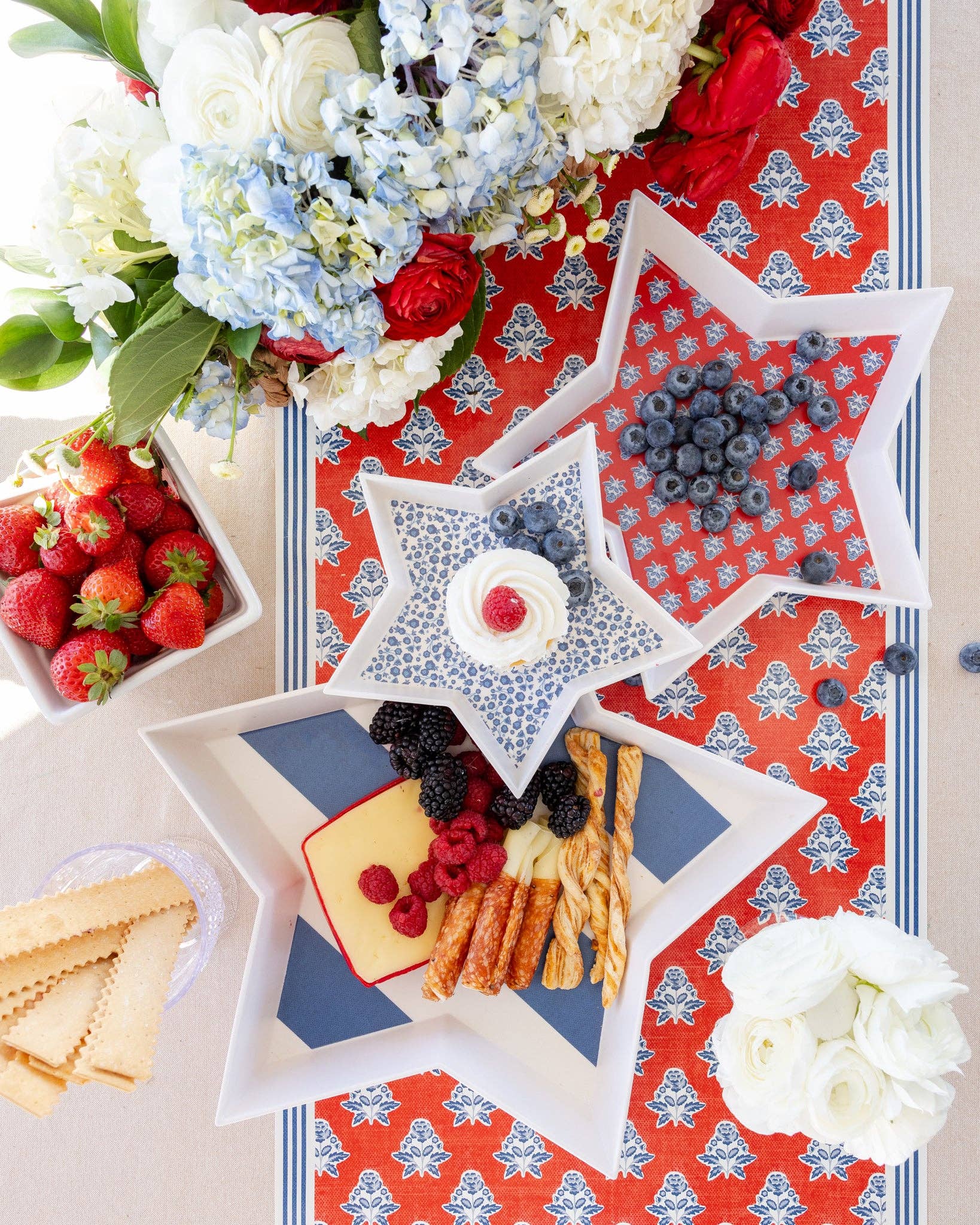 Star-shaped bamboo trays with snacks on a decorative tablecloth with flowers and berries.