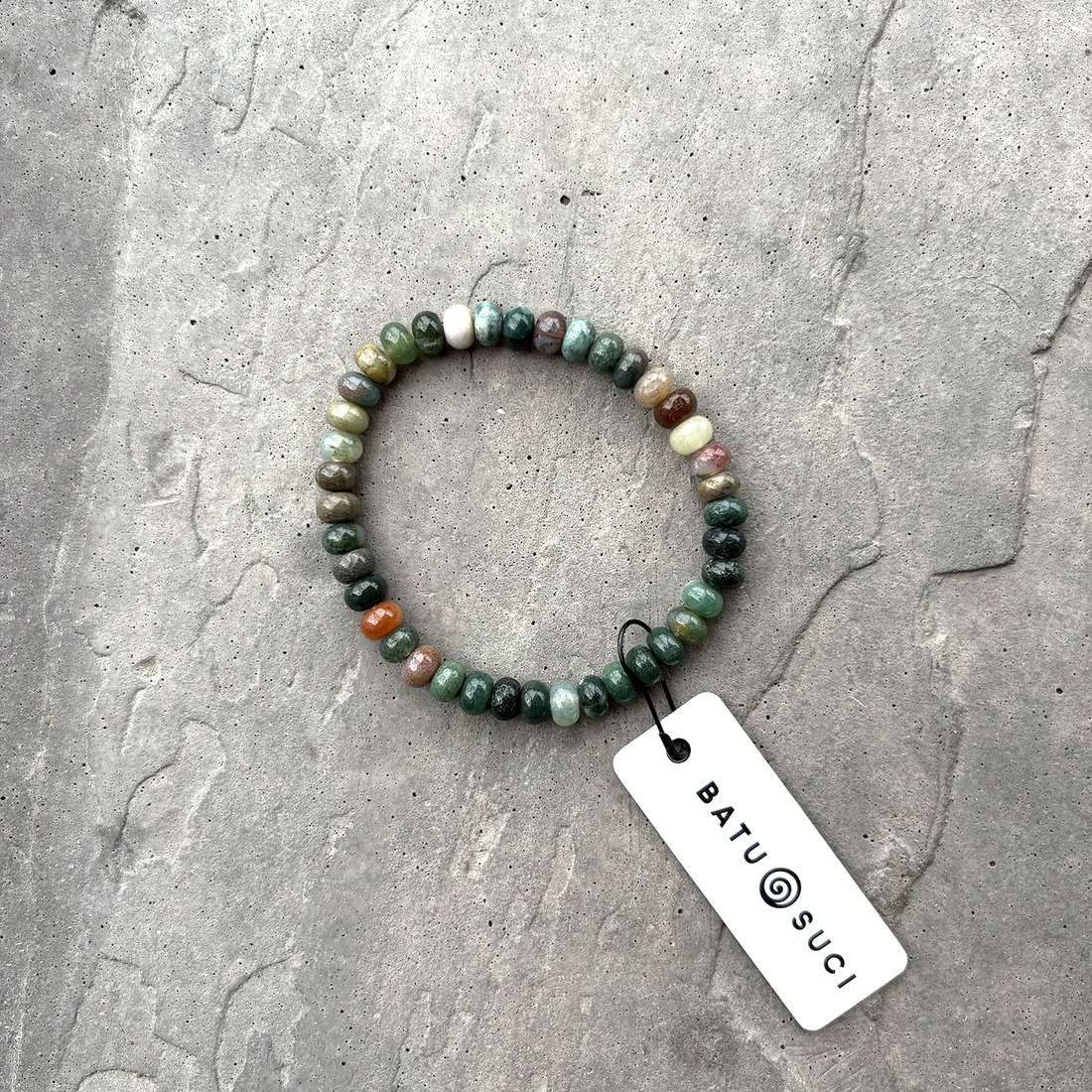Beaded bracelet with a tag on a textured surface