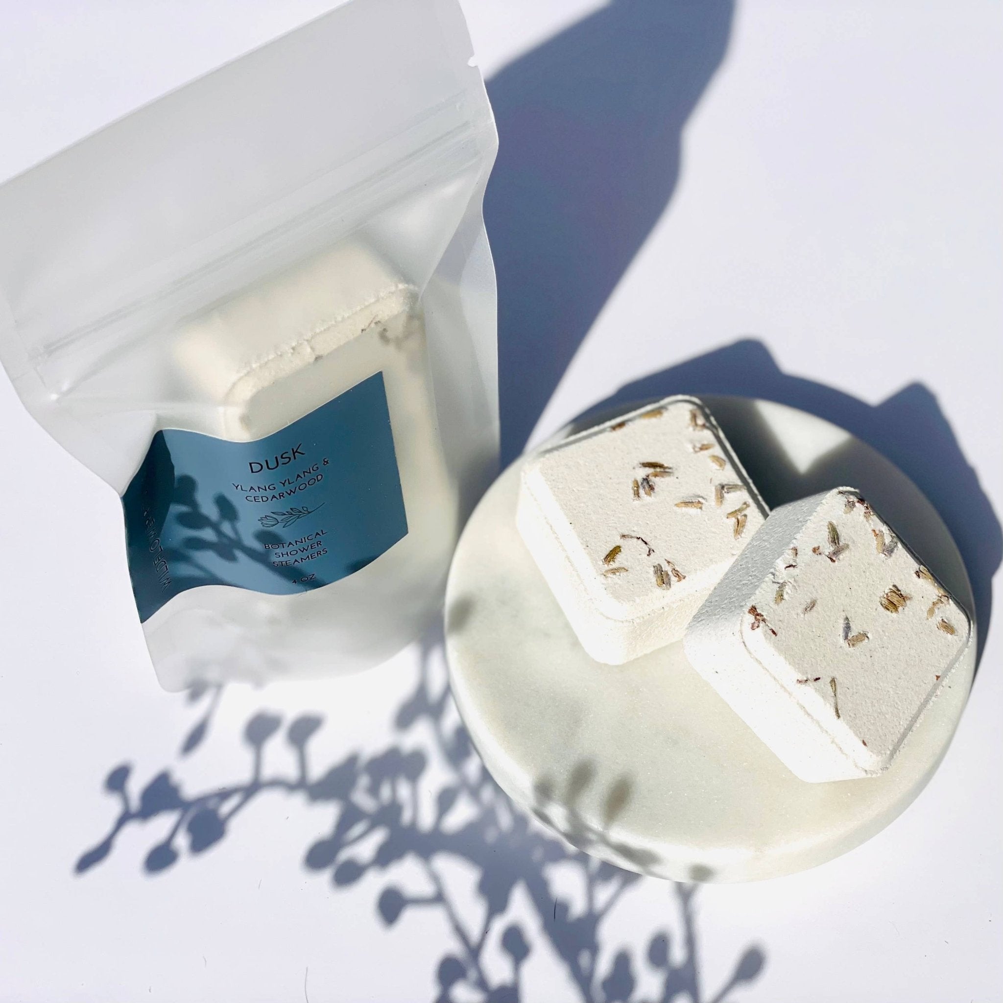 White shower steamers with floral elements on a white surface