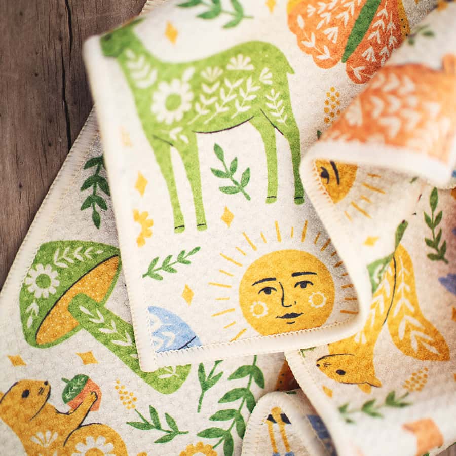 Colorful fabric patches with animal and sun designs on a wooden surface