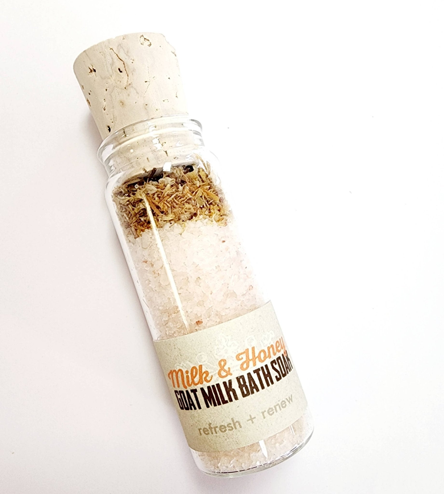 Three glass vials with cork lids, each filled with different bath soak blends. The vials are labeled with different scent combinations such as Milk & Honey and Rose & Lavender.