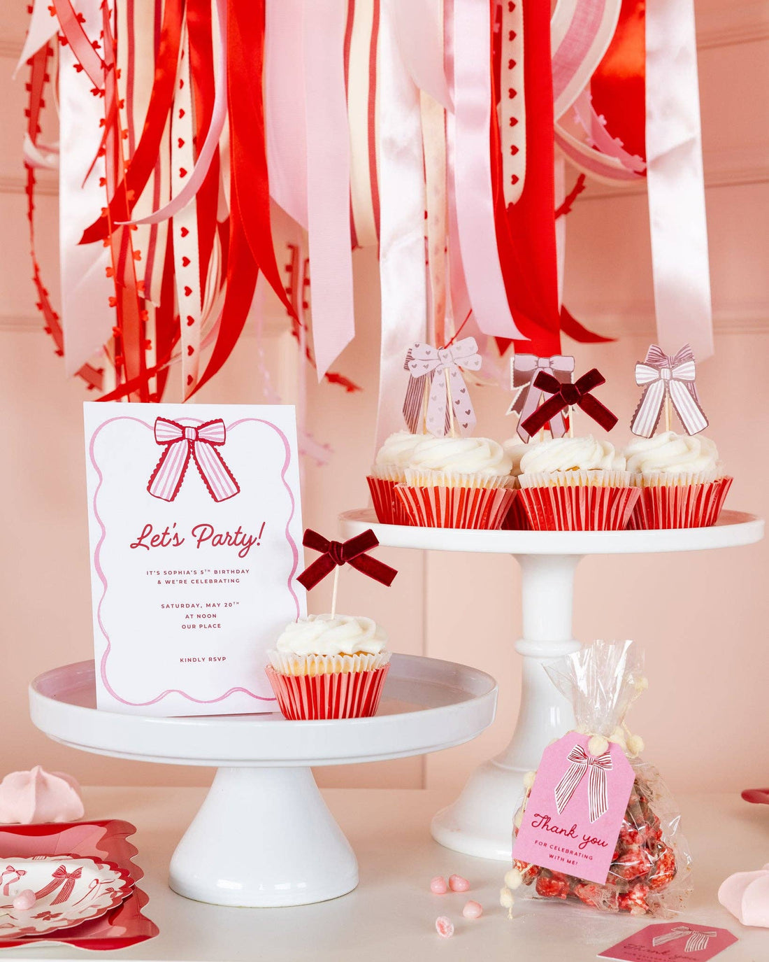 Decorative setup with cupcakes, ribbons, and a &