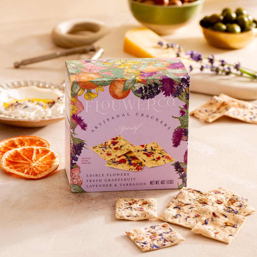 Box of Flowerco crackers on a table with crackers and snacks around