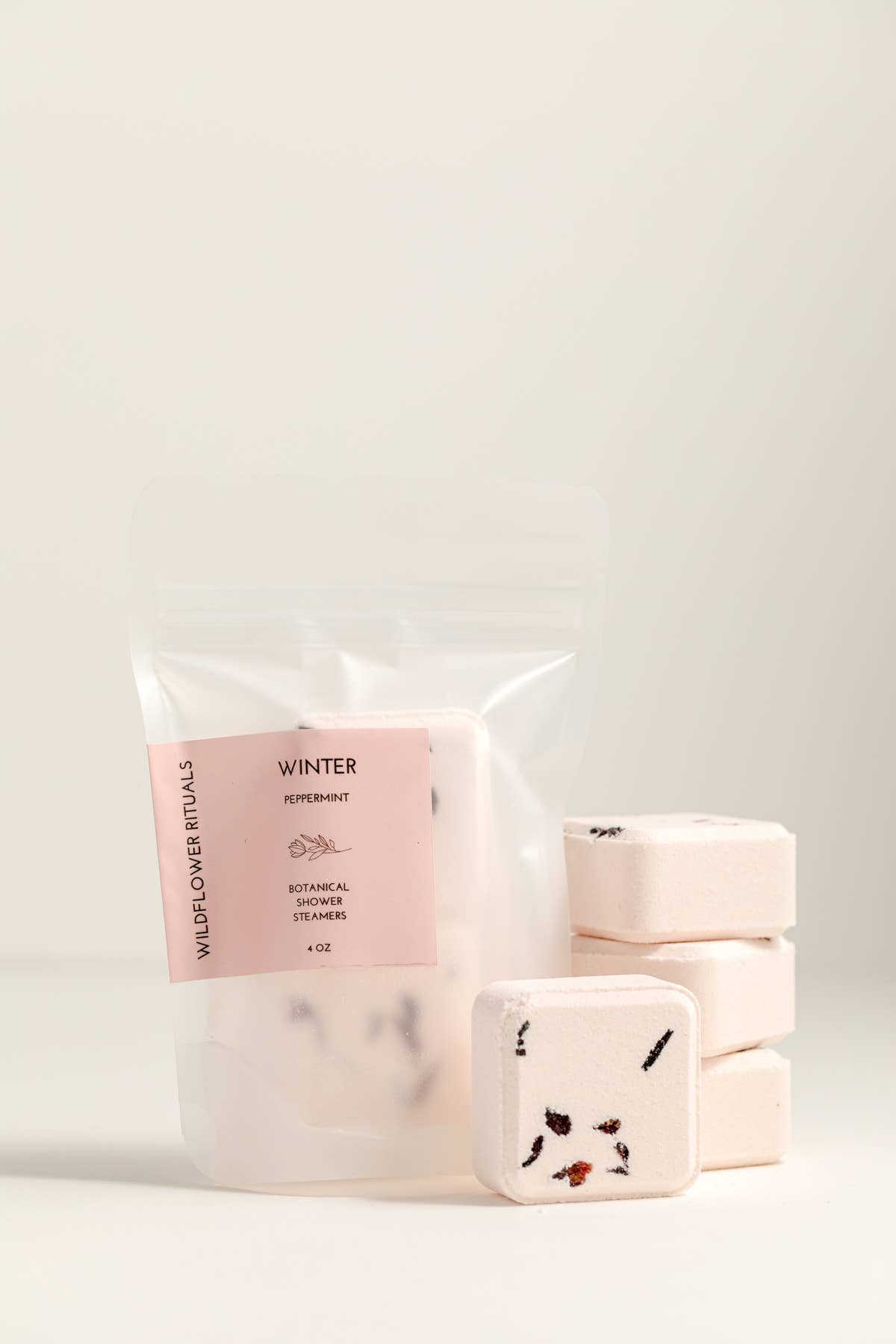 Packaged shower steamers with a pink label on a light gray background