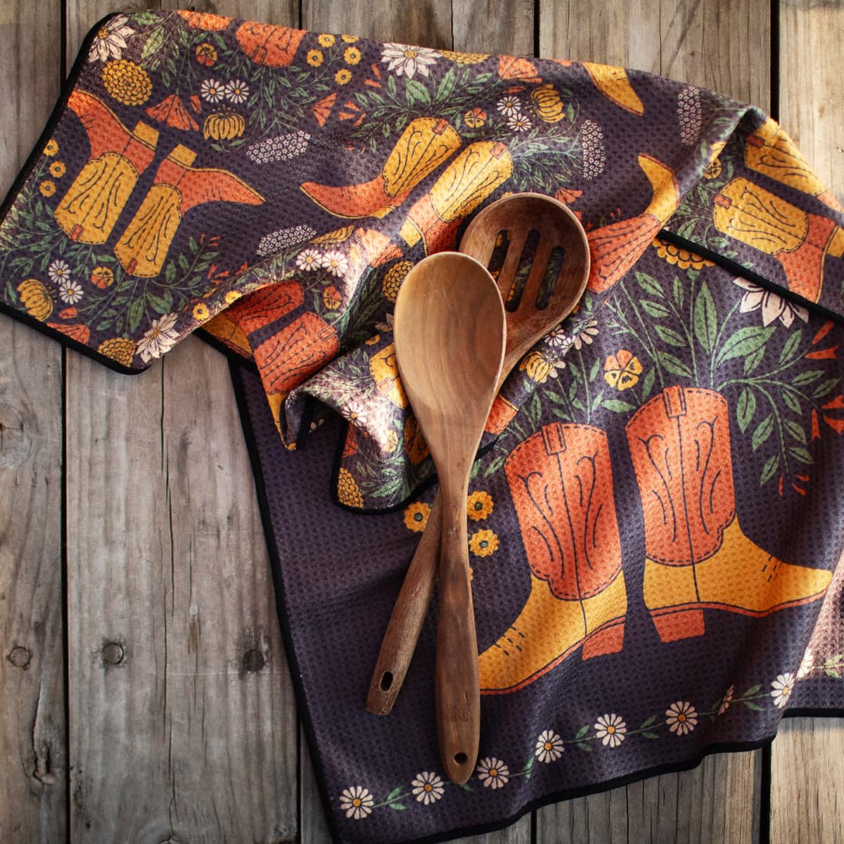 Colorful towel with cowboy boot design featuring wooden spoons on a wooden surface