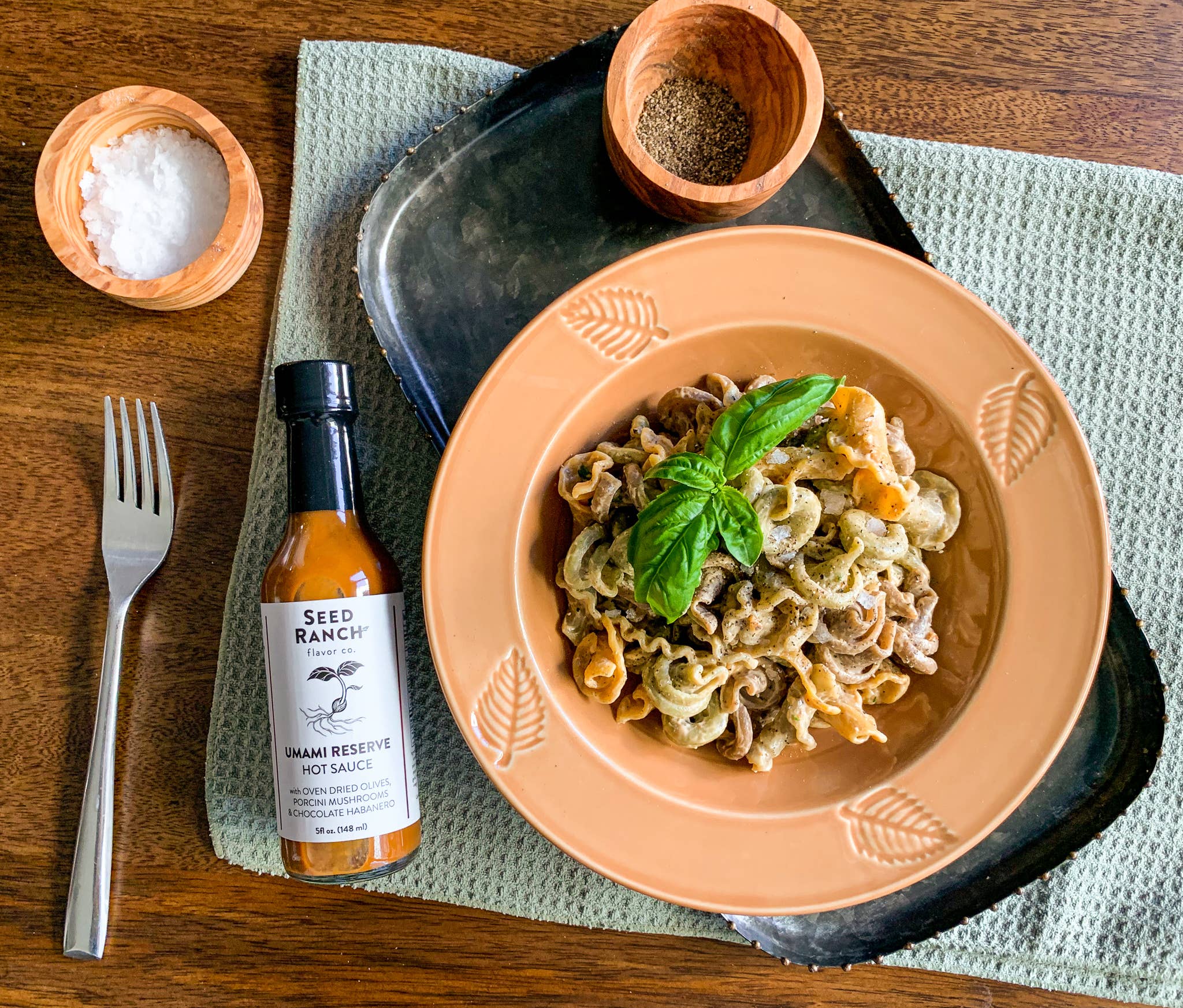 Pasta dish with hot sauce and condiments on a wooden table