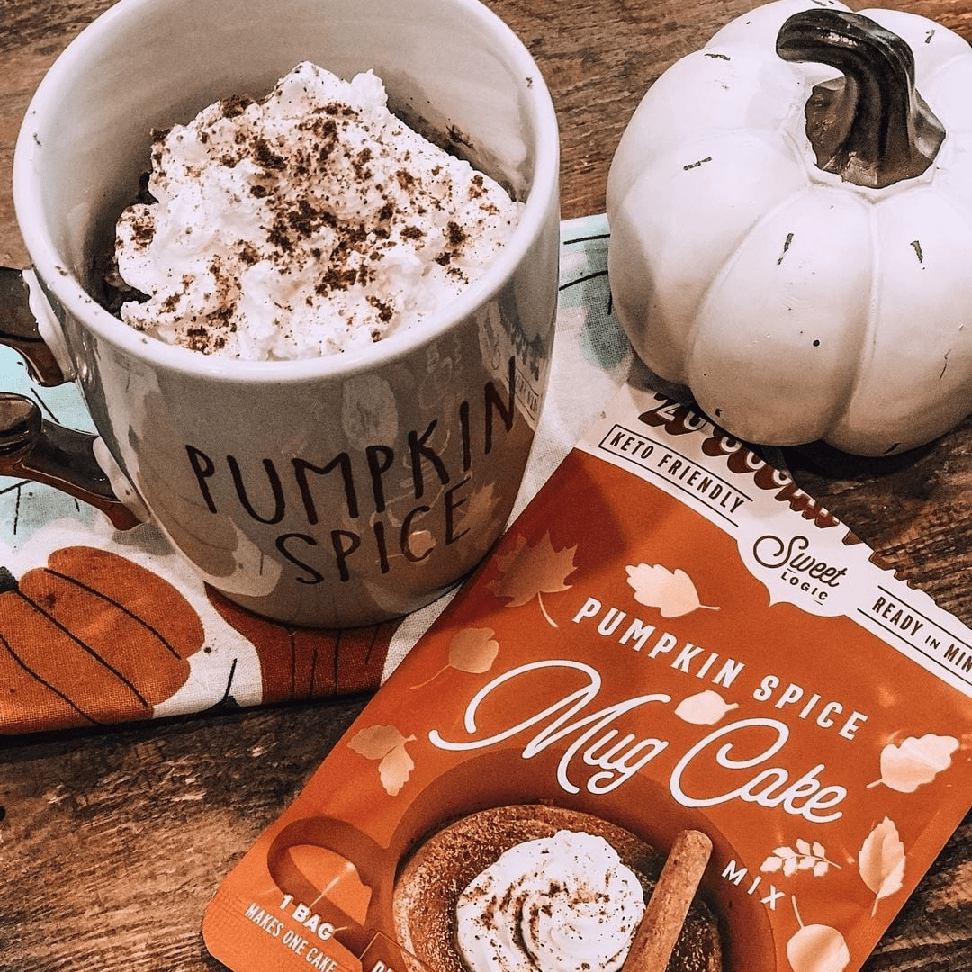 Pumpkin spice mug cake mix package with a pumpkin spice latte and decorative pumpkin on a wooden surface