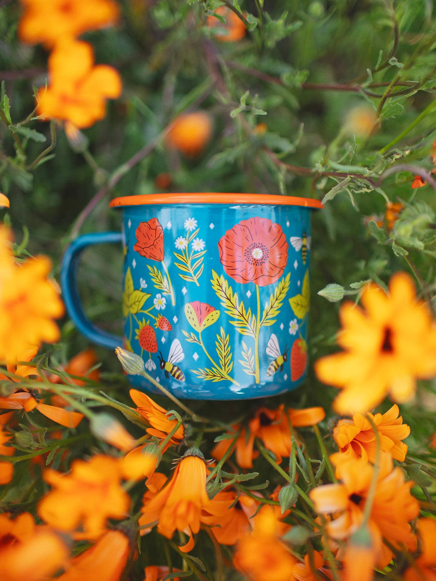 Blue mug with floral design on a bed of orange flowers