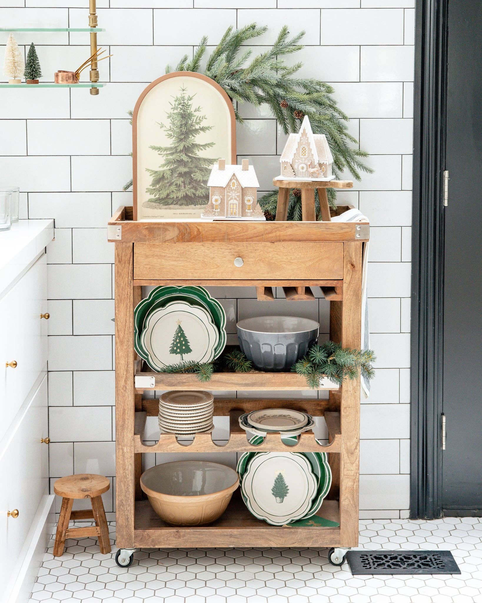 Wooden kitchen cart with festive decor against a white tiled wall.