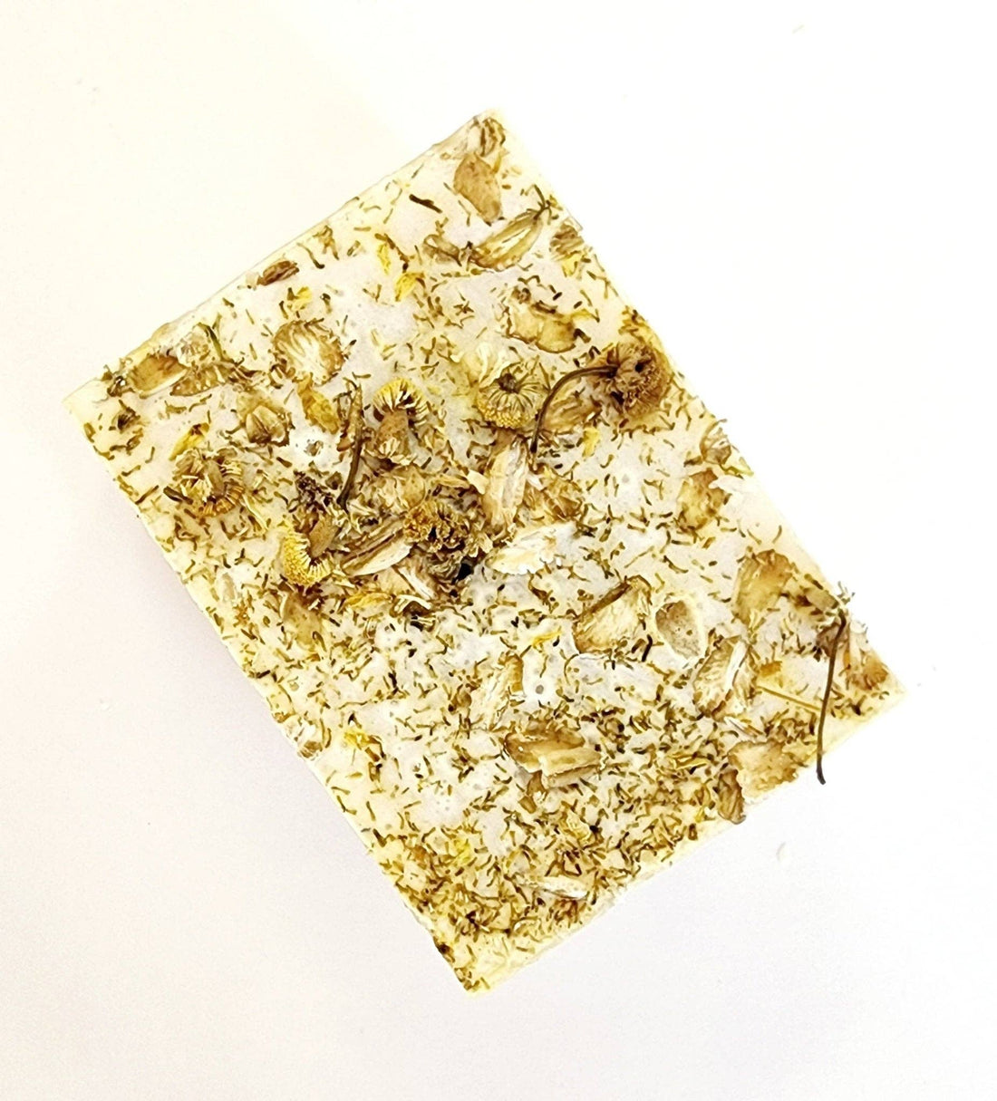 Rectangular bar of soap with pressed flowers and oatmeal on a white background