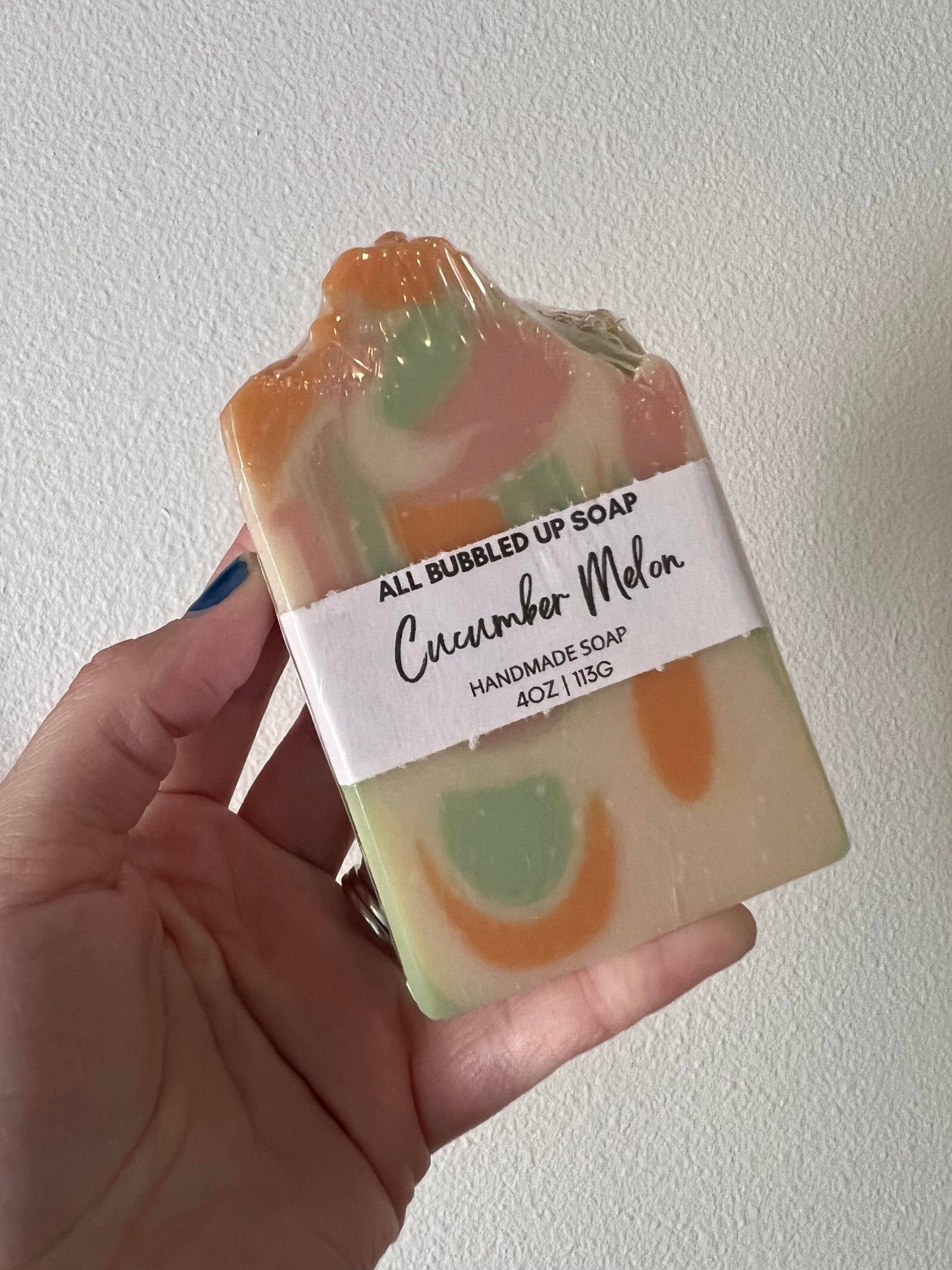 Handmade soap bar with a label held by a hand against a white background