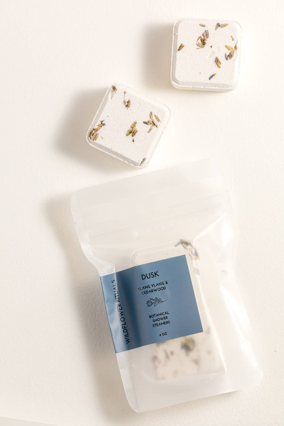 Three shower steamers with decorative packaging on a light background