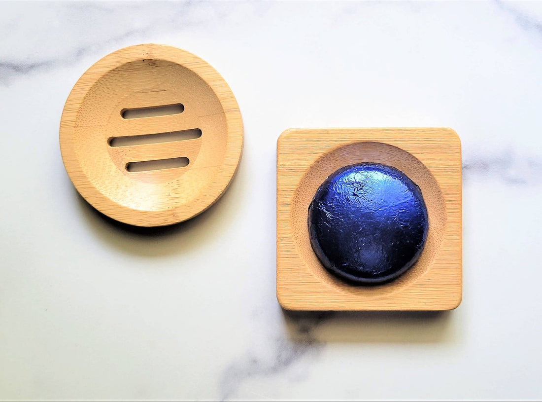 Wooden soap dish with a blue soap bar on a marble surface