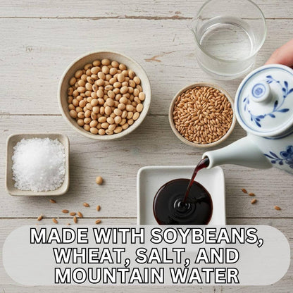 A styled overhead flat-lay of food ingredients and a teapot on a whitewashed wood surface. Bowls contain soybeans, wheat grains, coarse salt, and dark soy sauce, with water being poured from a blue-and-white ceramic teapot into a small dish.