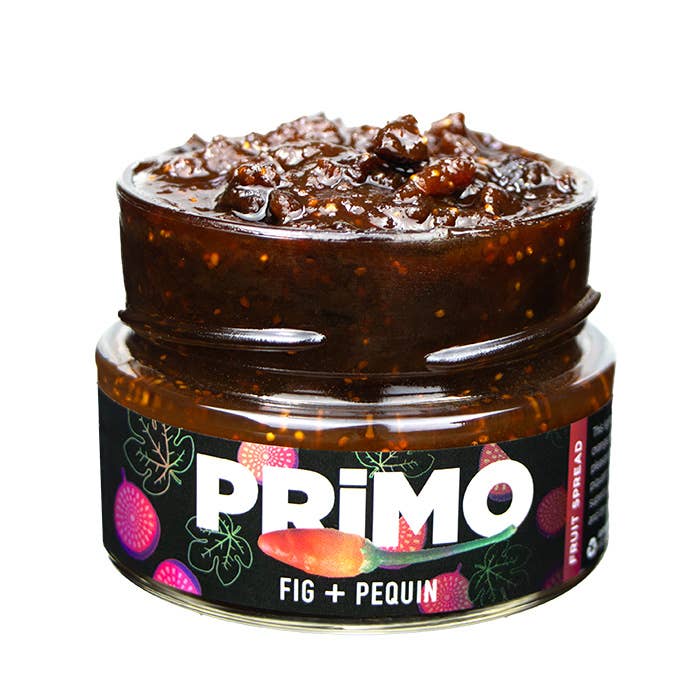 A jar of Primo Fig + Pequin Preserves with a label showing the product name and images of figs and Pequin peppers.