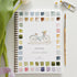 Spring watercolor workbook with a bicycle illustration and color swatches, surrounded by art supplies on a white surface.