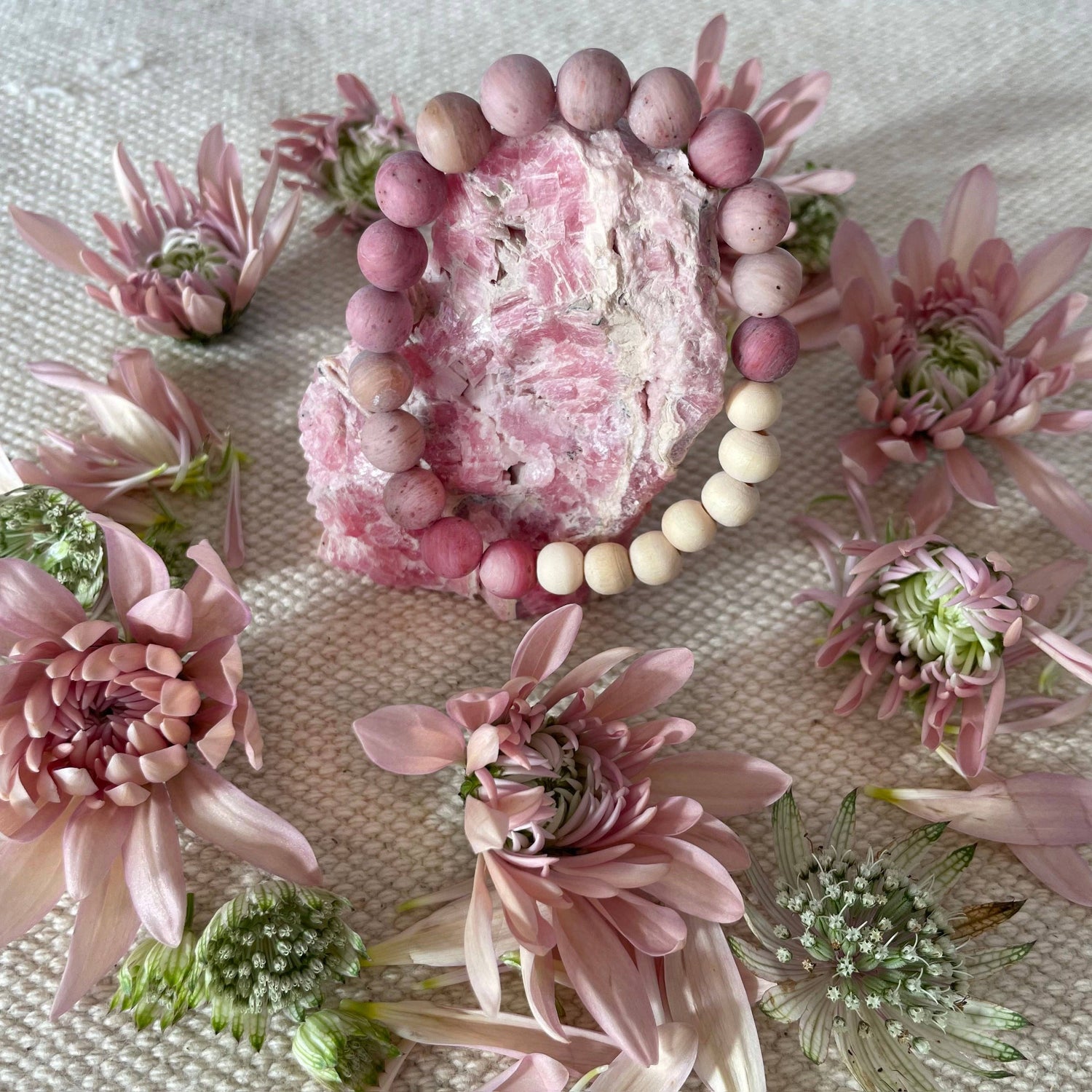 Pink beaded bracelet with pink flowers on a textured surface