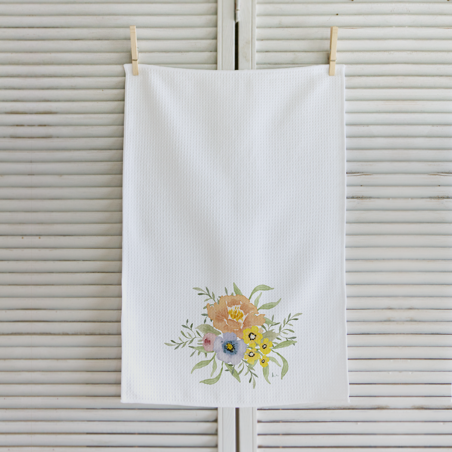 White towel with floral design hanging on a wooden surface
