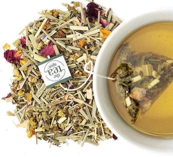 Herbal tea leaves and a cup of brewed tea with a &