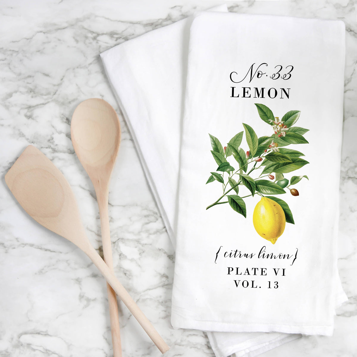 Tea towel with lemon design and wooden spoons on a marble surface