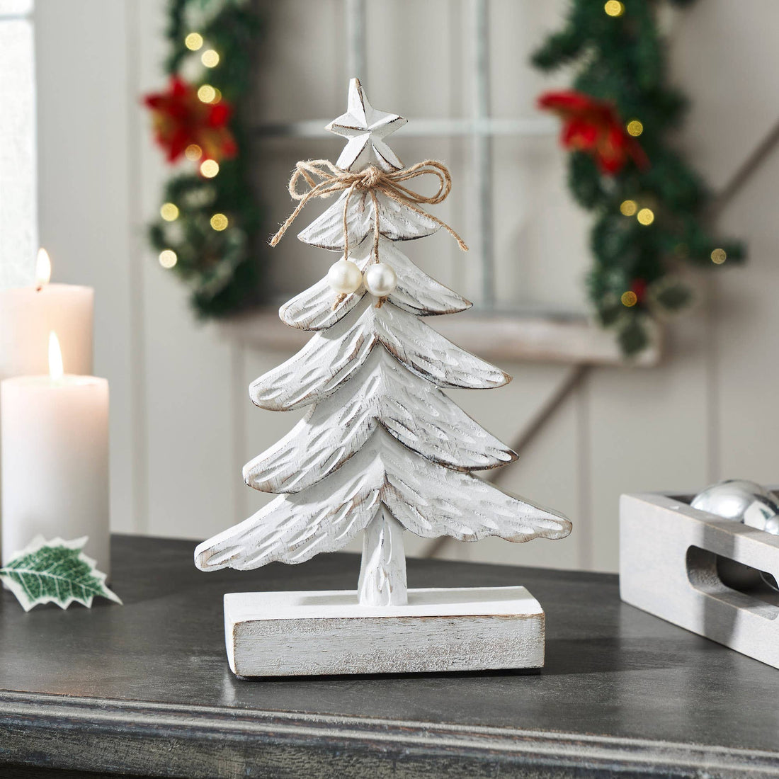 Decorative white Christmas tree figurine on a table with festive background