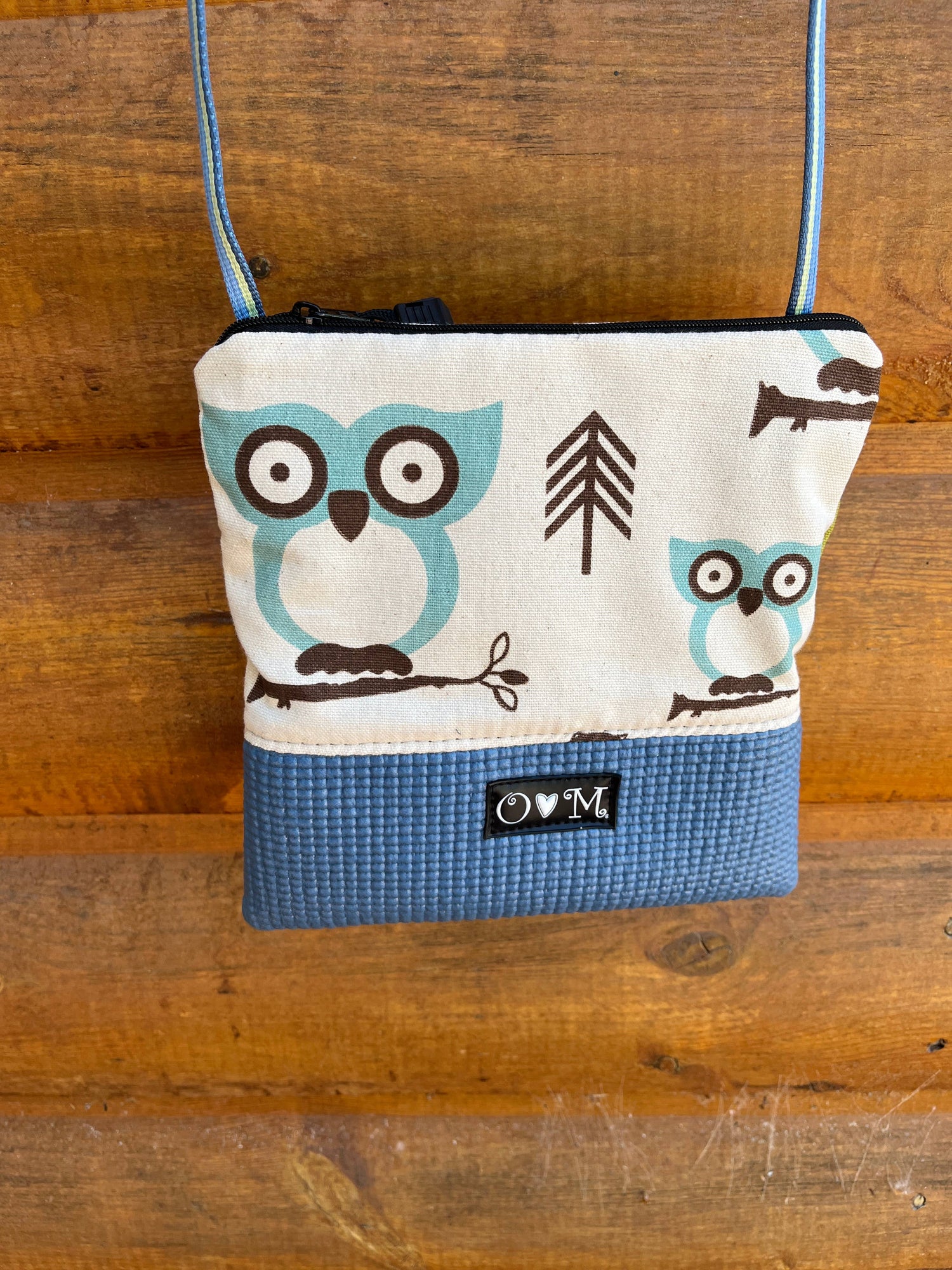 Small crossbody bag with owl design on a wooden surface
