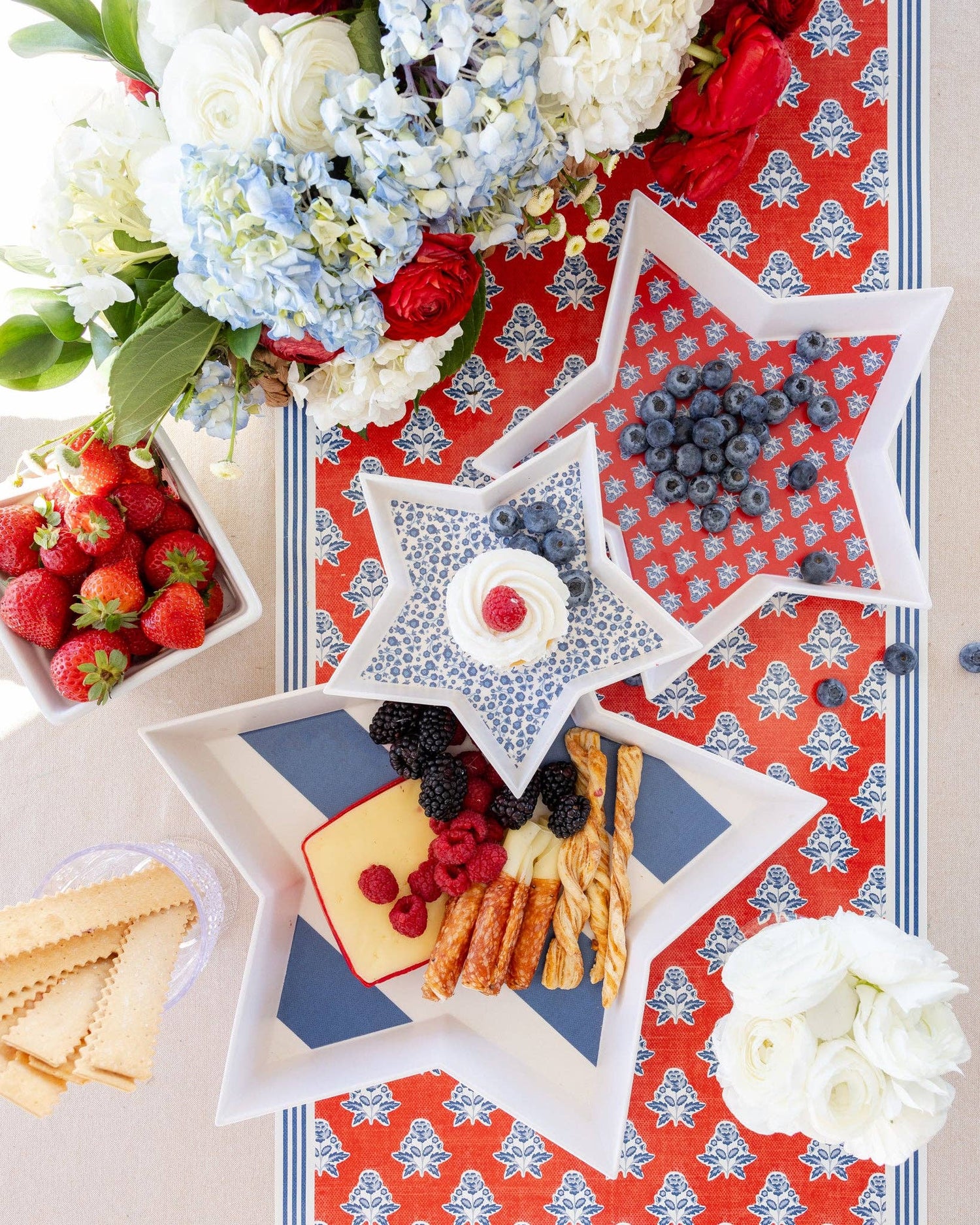 Star-shaped bamboo trays with snacks on a decorative tablecloth with flowers and berries.