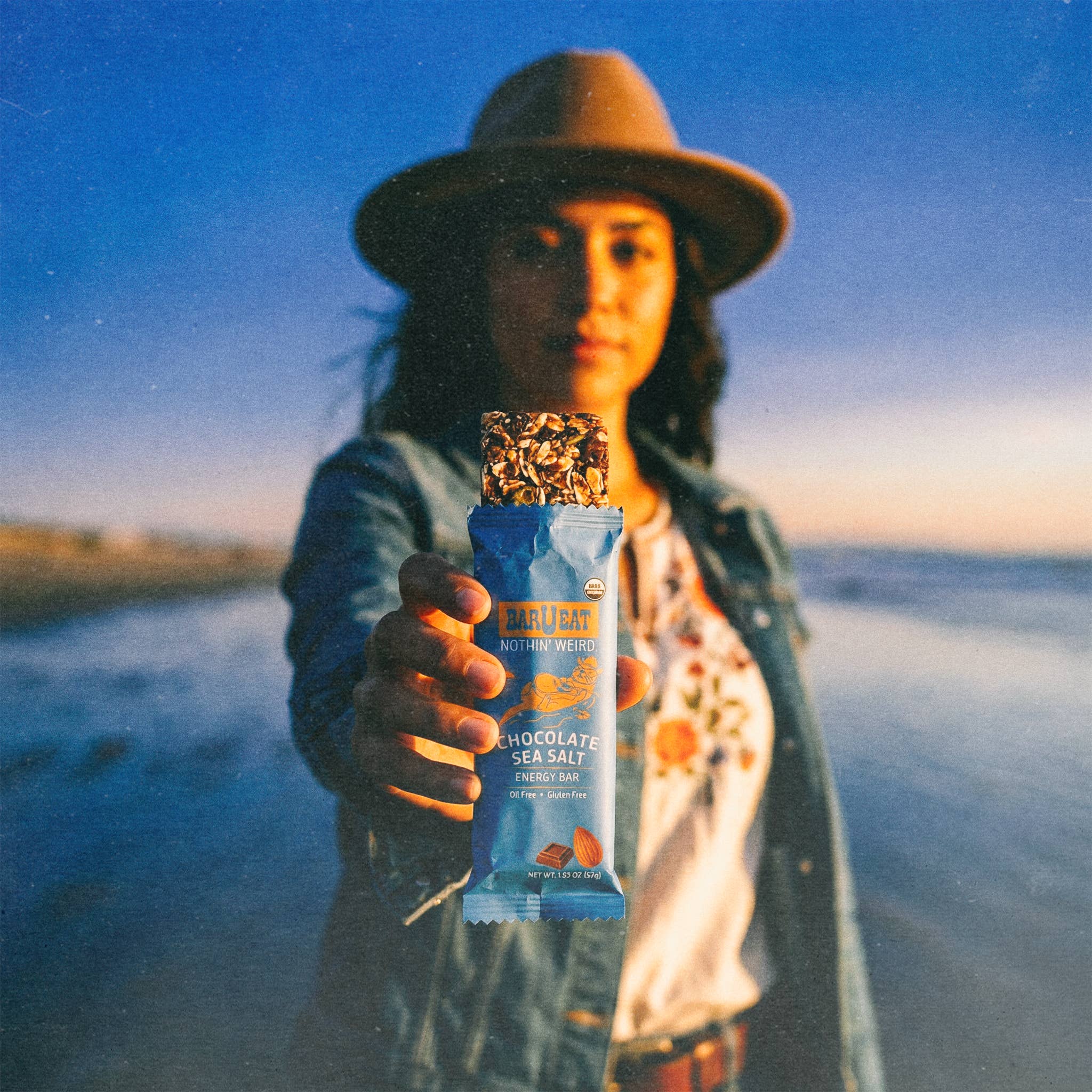 Person holding a chocolate sea salt snack bar against a scenic background