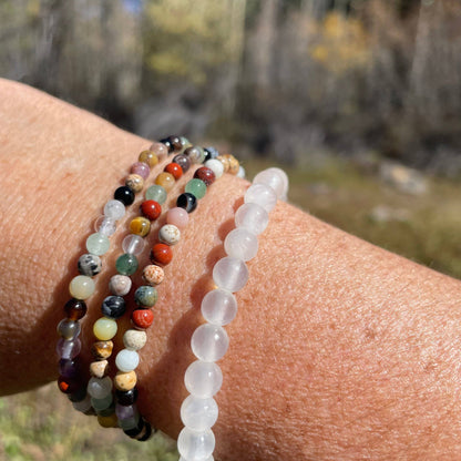 Close-up of a wrist wearing four beaded bracelets with a natural background