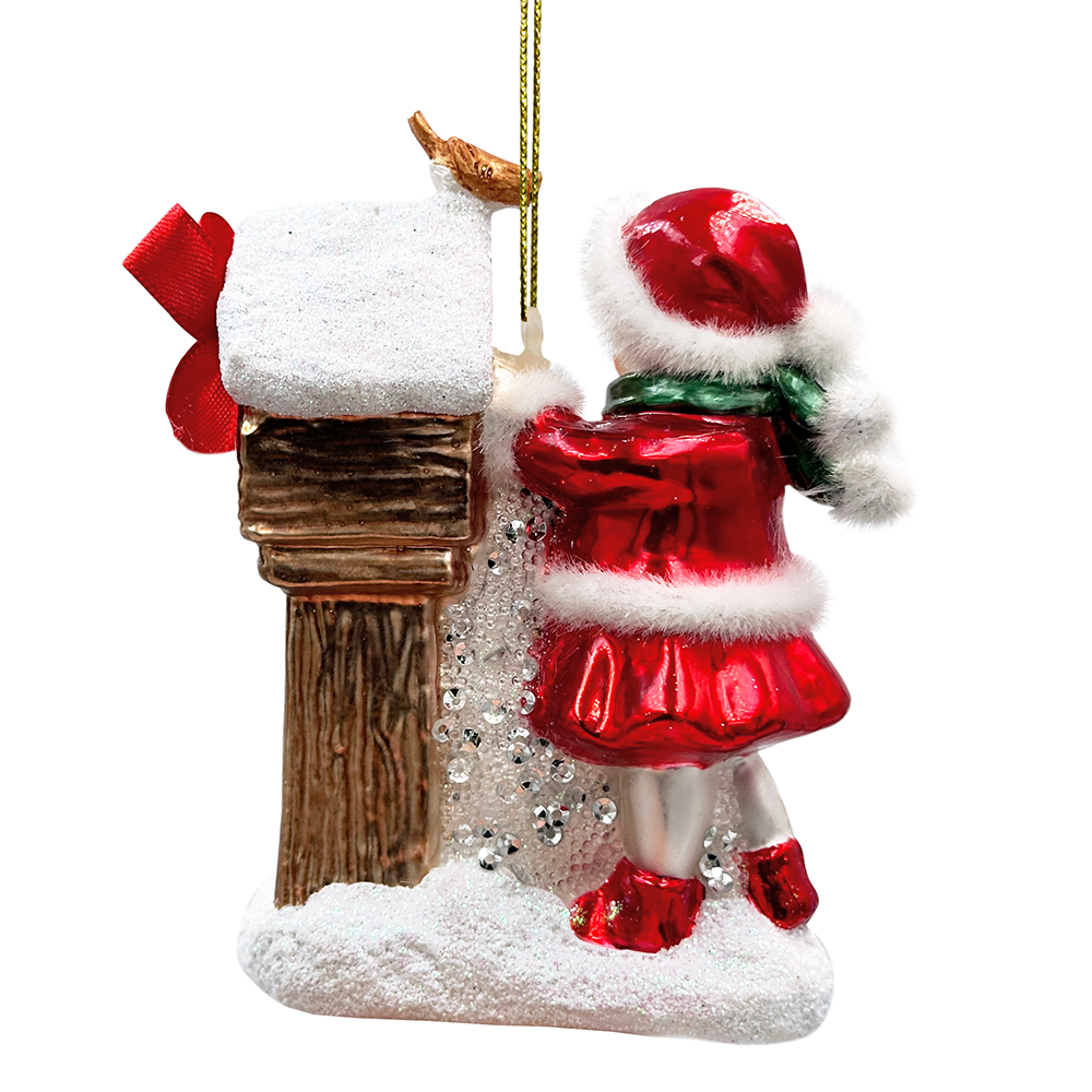 Christmas ornament of a child in a red coat standing next to a wooden post with snow on a white background