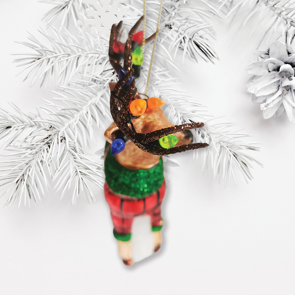 Decorative Christmas ornament of a lobster in human clothing hanging on a white Christmas tree.