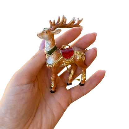 Decorative deer figurine held in a hand against a white background