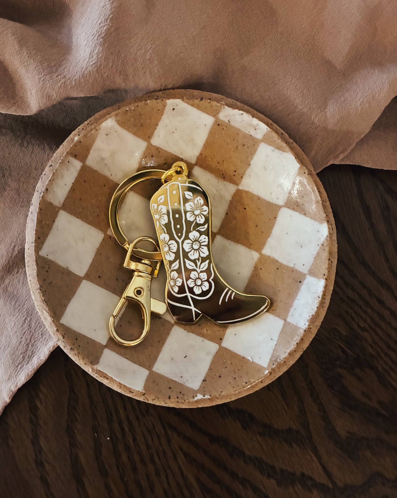Cowboy boot keychain with floral design on a checkered ceramic plate