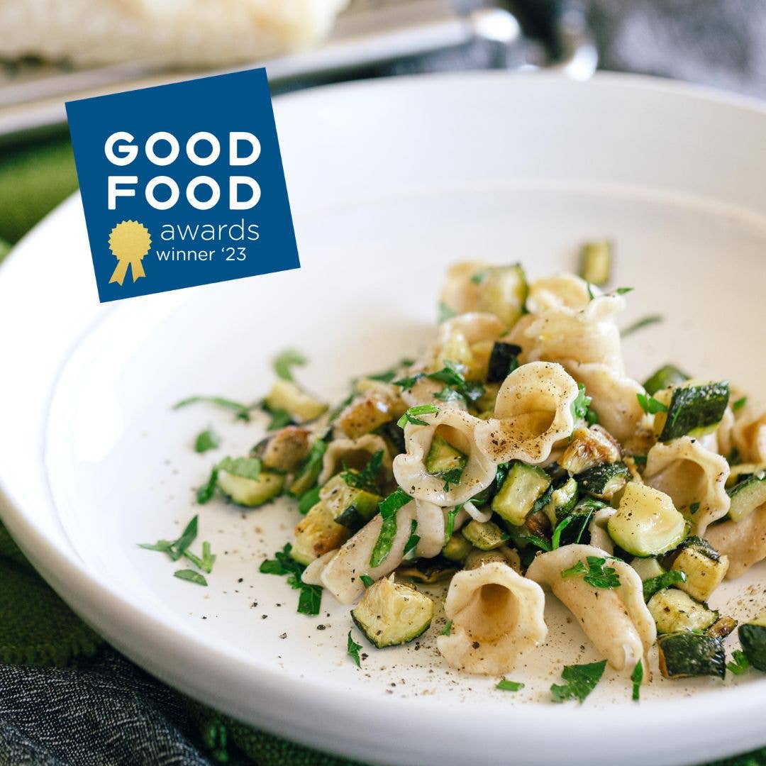 Pasta dish with zucchini and herbs on a white plate, featuring the Good Food awards logo.