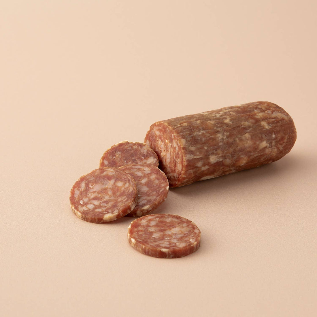 Salami with slices on a beige background