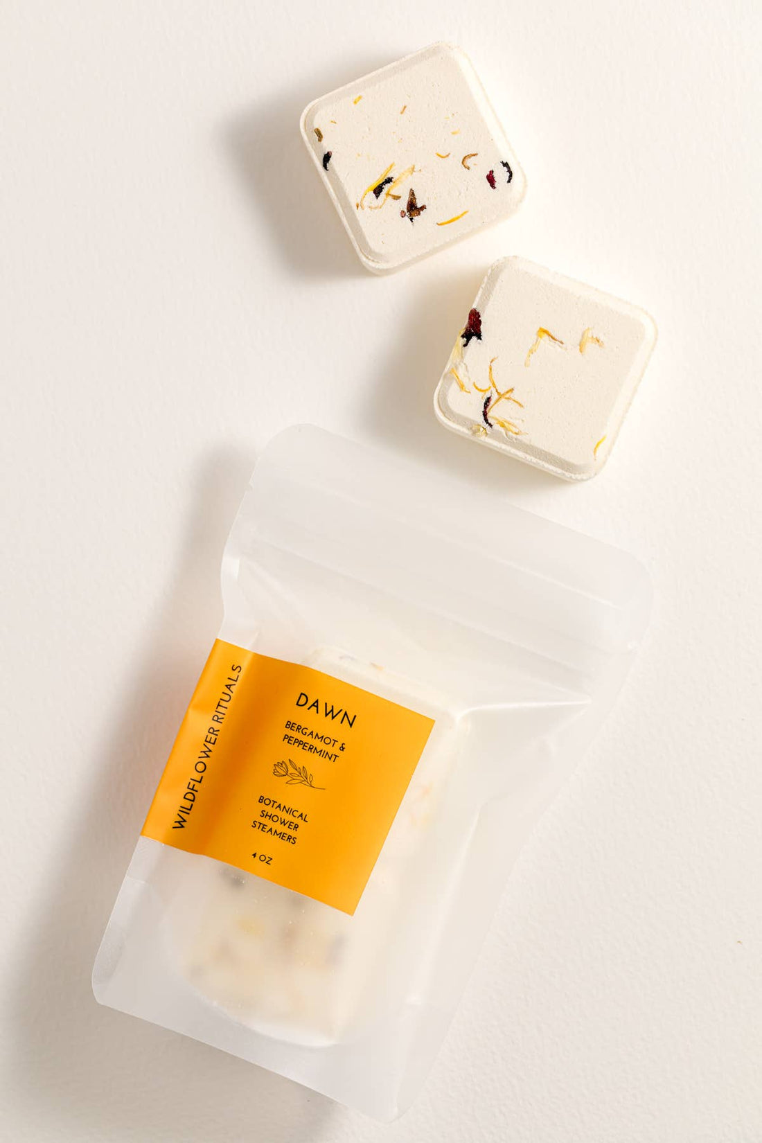 Two shower steamers with decorative packaging on a light background