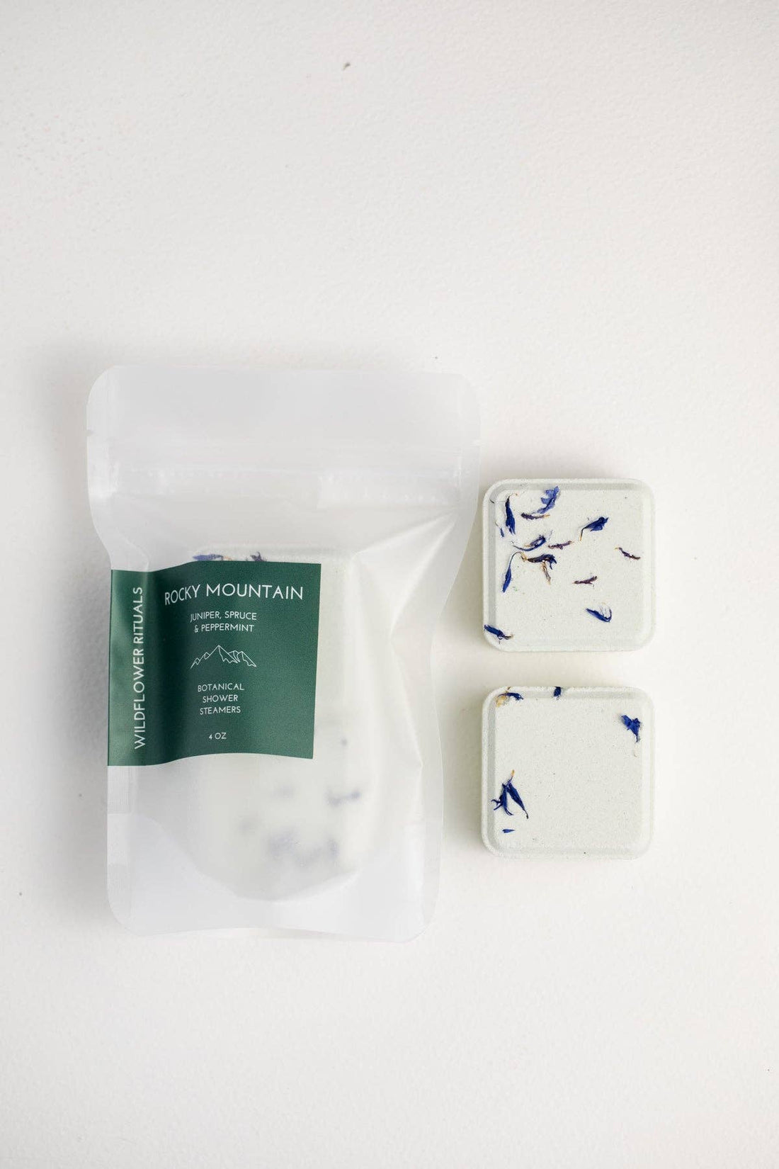 Two shower steamers with floral design on a white background, one still in packaging.