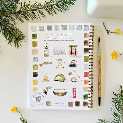 Artistic coloring book with watercolor illustrations on a white surface with decorative elements.