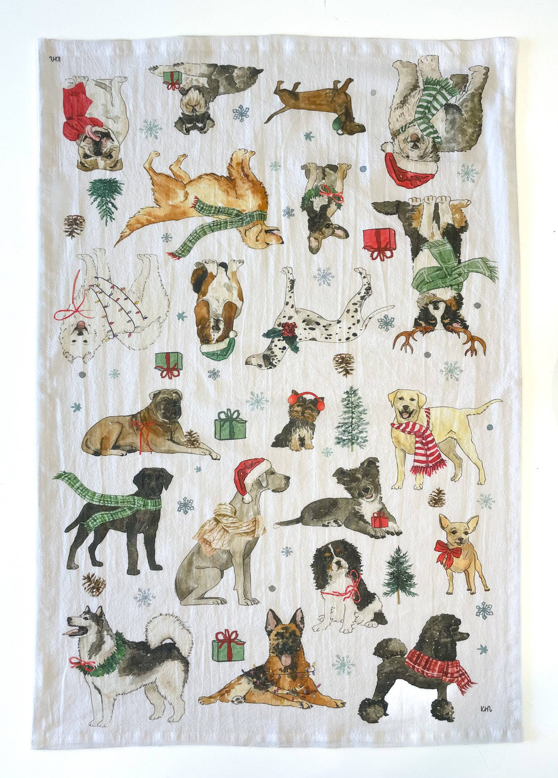 Tea towel with Christmas-themed dogs wearing scarves and hats on a white background