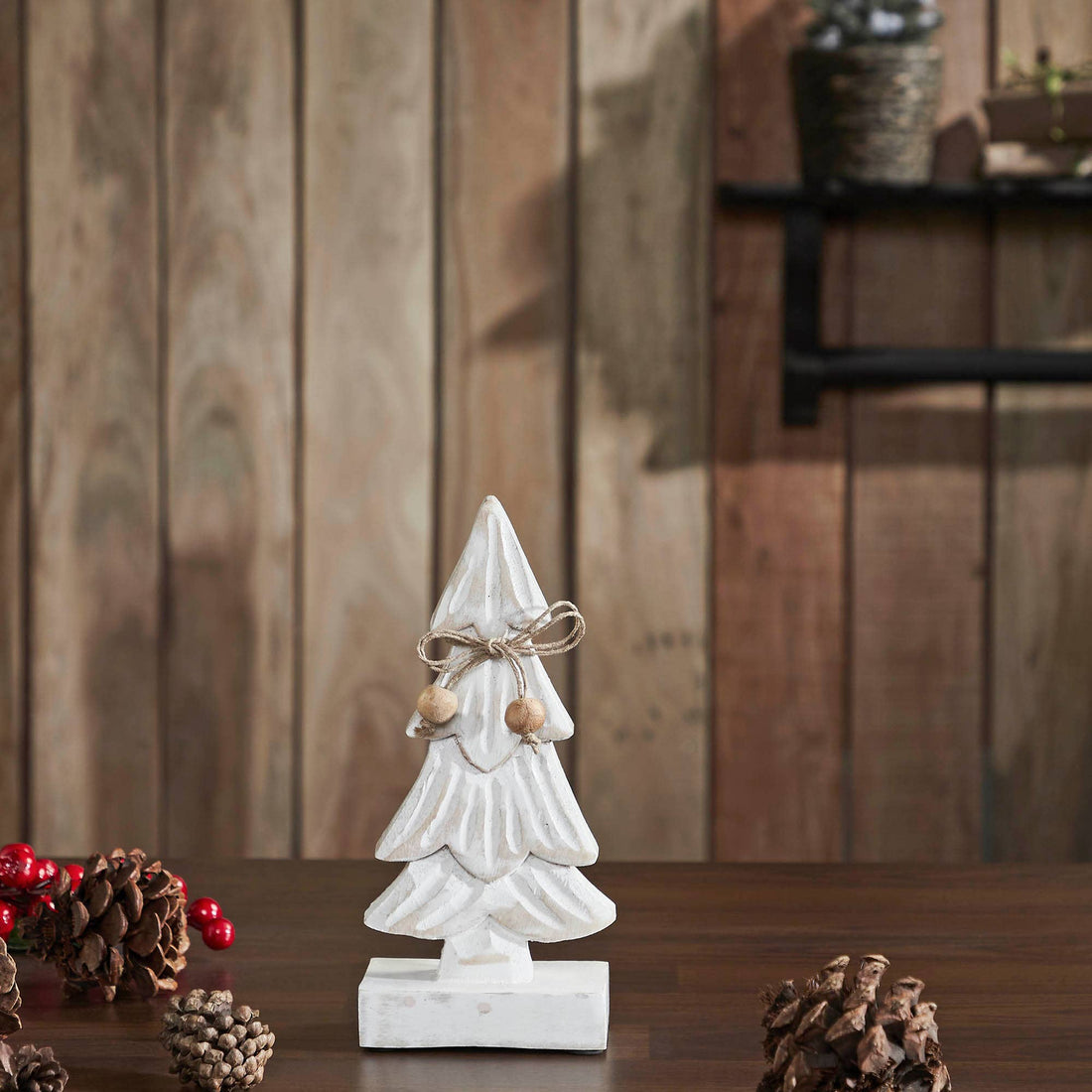 Decorative white Christmas tree figurine on a wooden surface with a rustic background