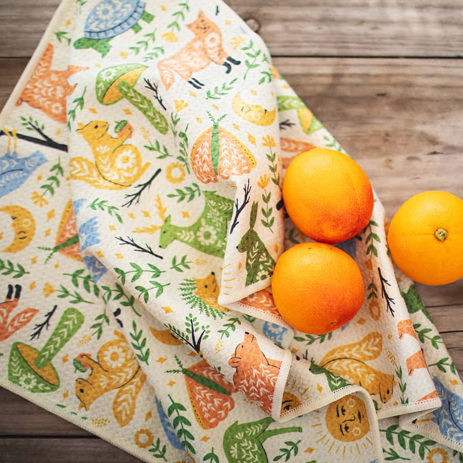 Patterned fabric with animal designs and oranges on a wooden surface