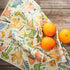 Patterned fabric with animal designs and oranges on a wooden surface