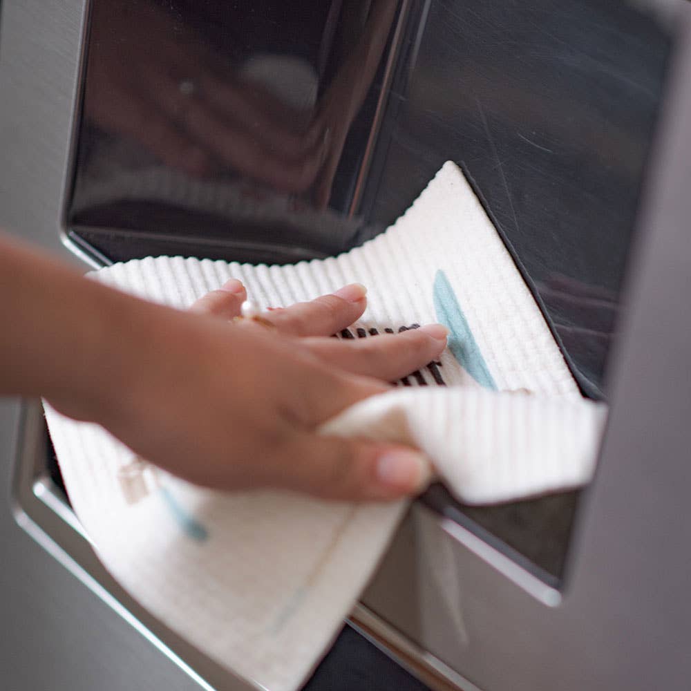 Person cleaning a microwave with a cloth