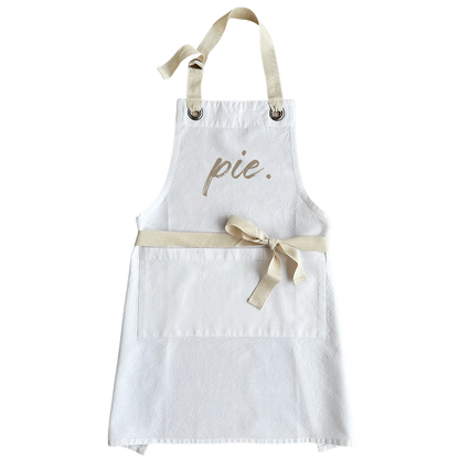 A white fabric apron with a beige neck strap and waist tie, featuring the word &