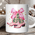 White mug with pink cowboy boots and a bow design on a wooden surface.