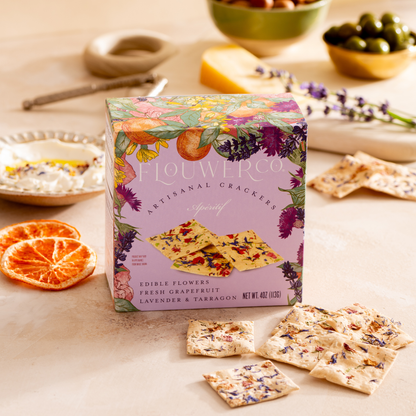 Box of Flowerco crackers on a table with crackers and snacks around